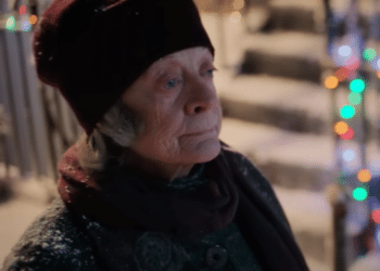 Zia Ruth (Maggie Smith) cammina lungo una strada piena di decorazioni natalizie nel film "Un ragazzo chiamato Natale".